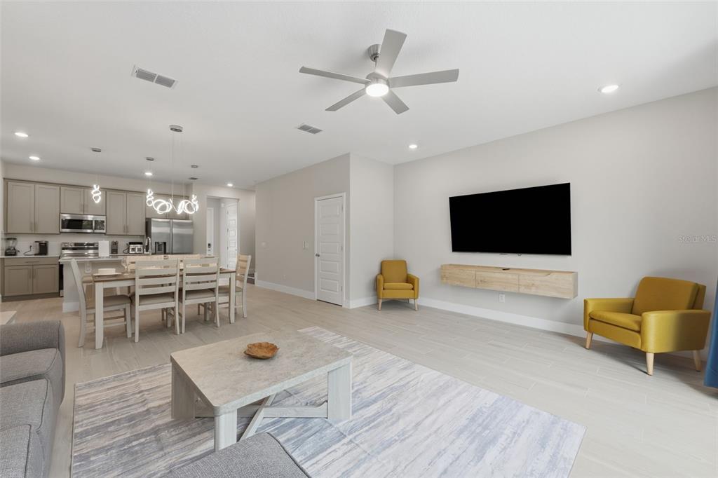 A living room and dining area feature light wood-look tile flooring and yellow accent chairs — 1216 ROYAL VIEW TERRACE, KISSIMMEE, FL