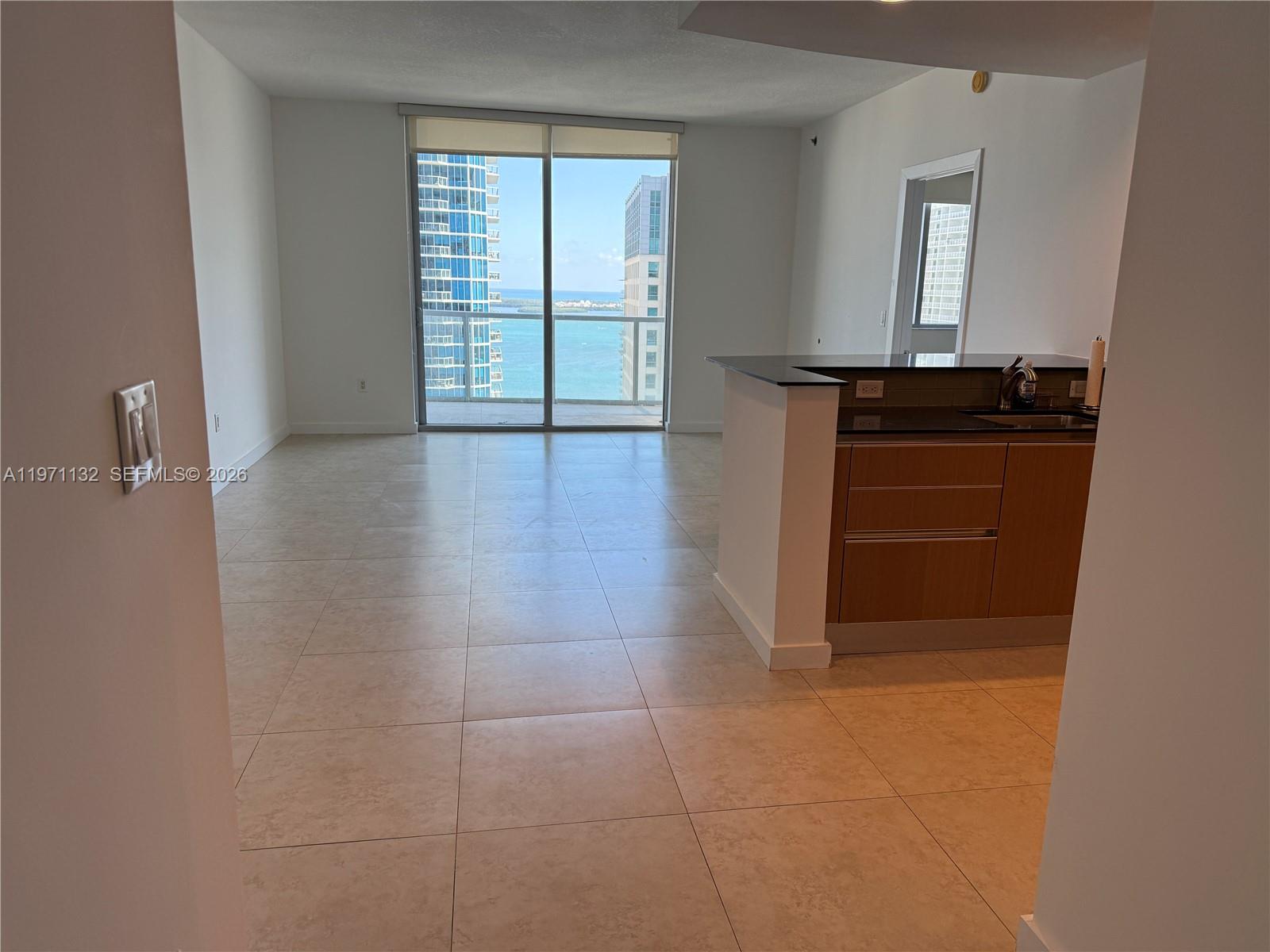 An open-concept living area features light tile flooring, a kitchen island, and floor-to-ceiling balcony windows — 1060 Brickell Ave # 3105, Miami FL 33131, MIAMI, FL