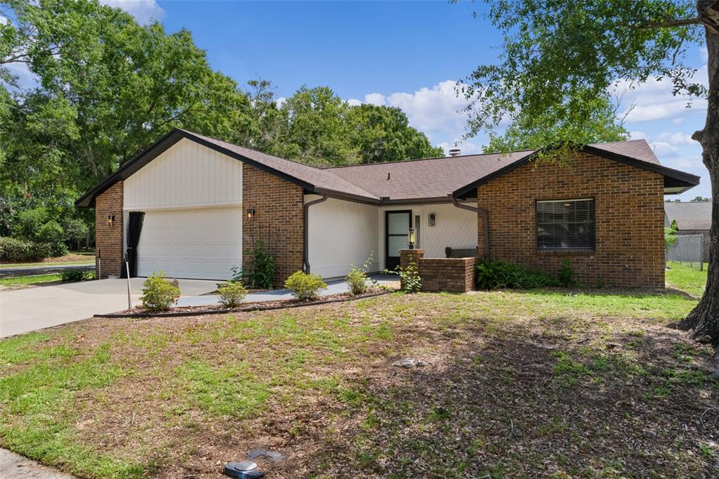 A single-story brick house with a white garage door and a front entryway — 1401 14TH STREET, CLERMONT, FL