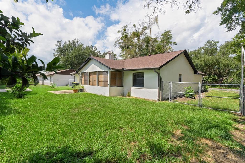 A single-story house with a screened-in porch and a chain-link fence in the backyard — 1401 14TH STREET, CLERMONT, FL