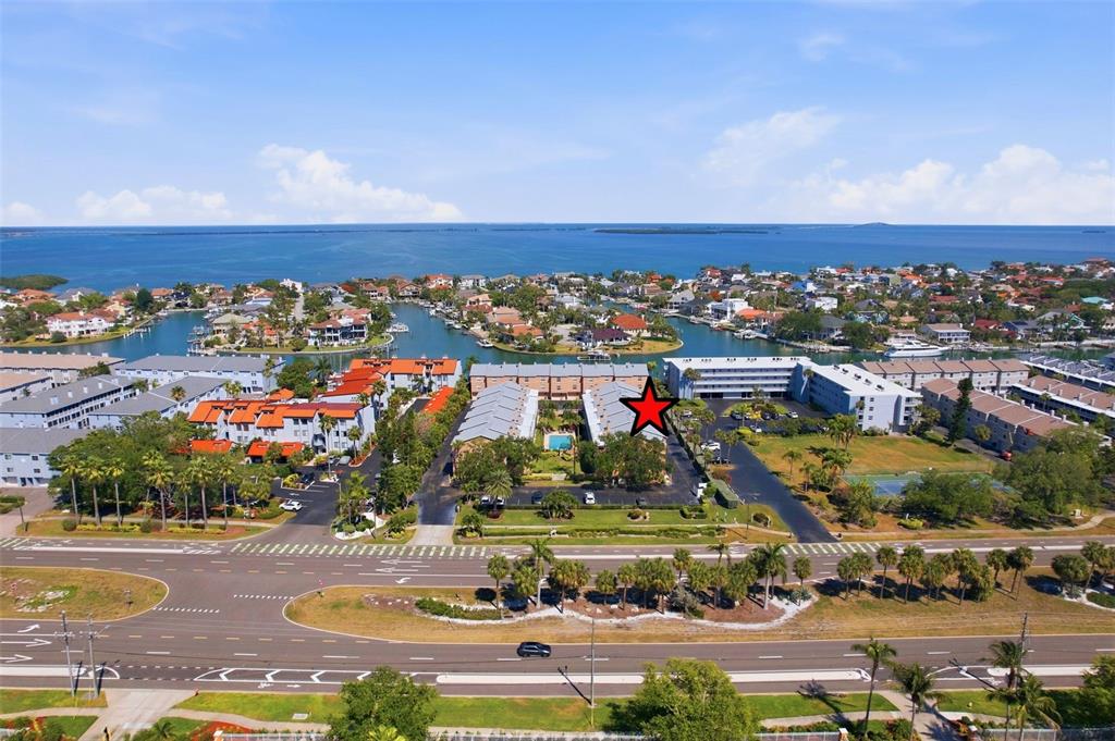 An aerial view shows a multi-story apartment complex with a red star marking a building — 637 PINELLAS BAYWAY S UNIT 207, TIERRA VERDE, FL