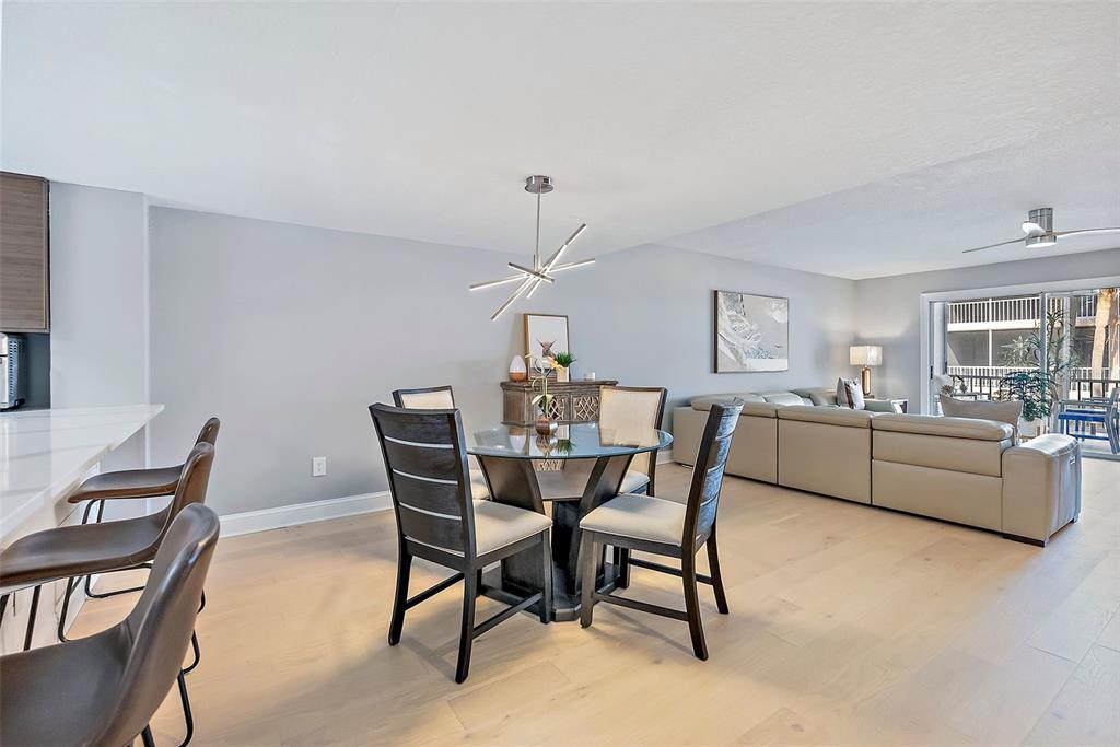An open-concept living and dining area features light wood flooring and modern neutral furniture — 637 PINELLAS BAYWAY S UNIT 207, TIERRA VERDE, FL