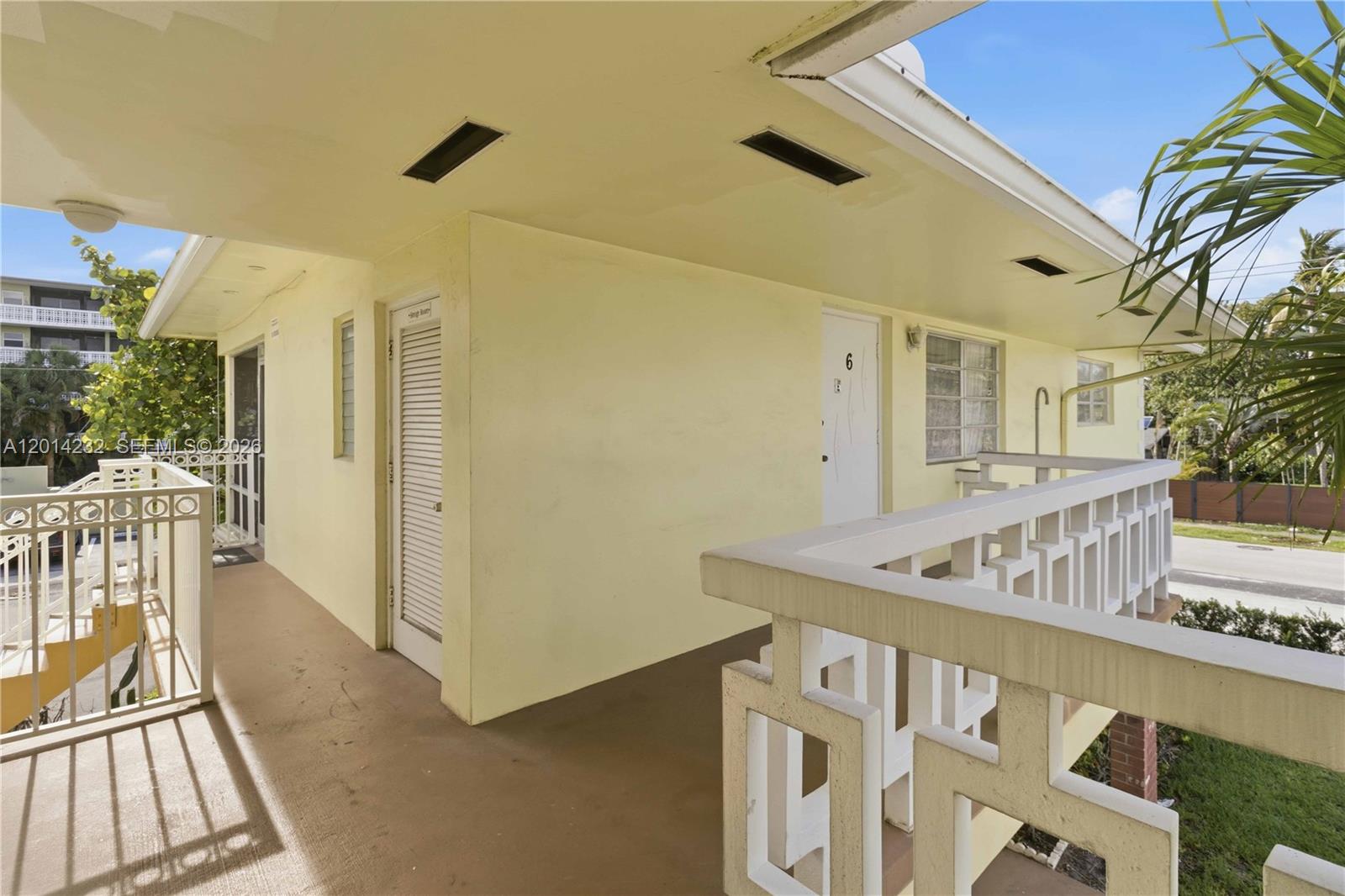 An exterior walkway with a white railing leads to a door marked number six — 1501 Arthur St # 6, Hollywood FL 33020, HOLLYWOOD, FL