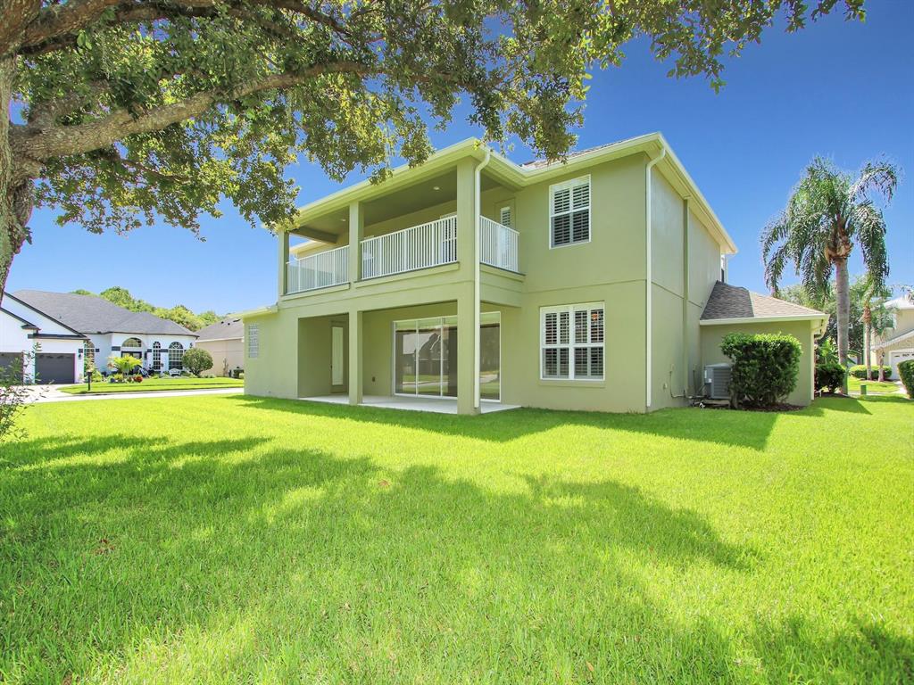 The exterior of a two-story green house with a covered patio and a second-floor balcony — 10093 CHARDONNAY DRIVE, ORLANDO, FL
