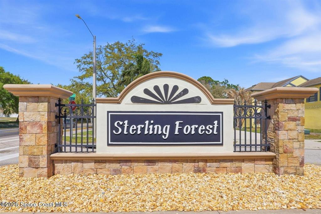 A stone monument sign with black metal fencing marks the entrance to Sterling Forest — 5327 ENCHANTED AVENUE, TITUSVILLE, FL