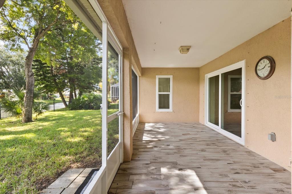 A covered patio with wood-look tile flooring, a screen door, and a view of the yard — 410 CENTRAL MARINERS DRIVE, EDGEWATER, FL