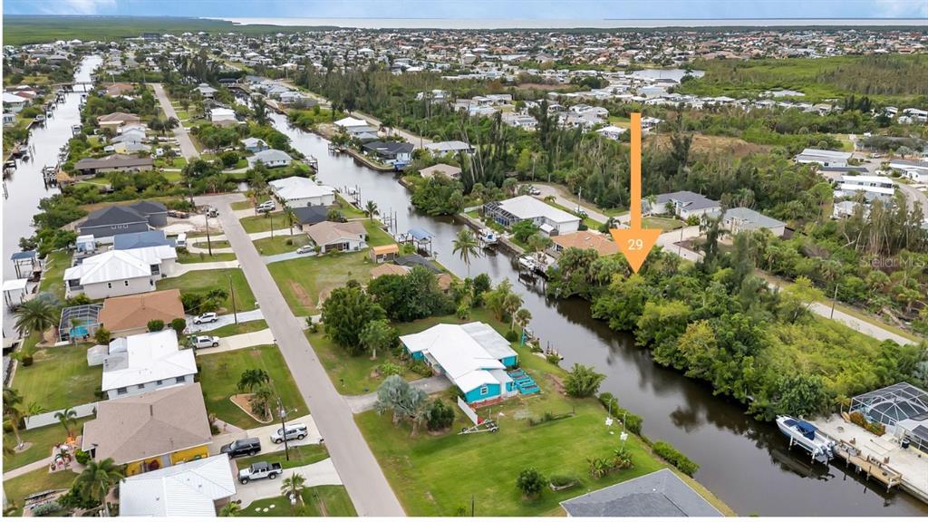 An aerial view shows a canal-front residential lot marked with an orange arrow — 3420 COLONY COURT, PUNTA GORDA, FL