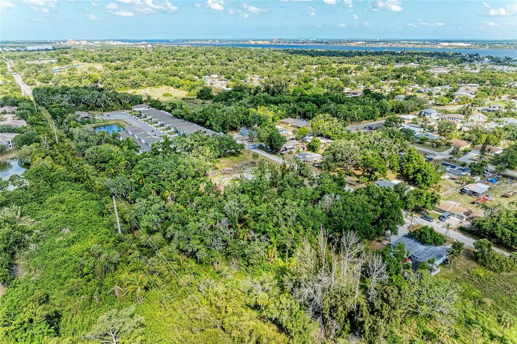 An aerial view shows a wooded lot adjacent to a residential neighborhood and water — 3006 12TH AVENUE E, BRADENTON, FL