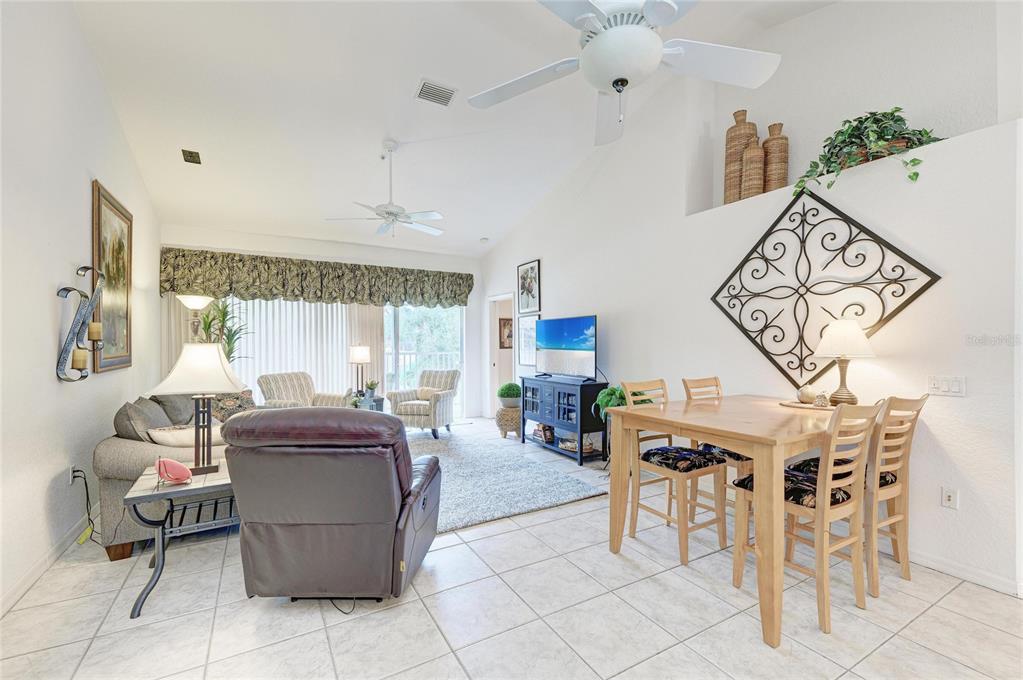 A living and dining area features vaulted ceilings, tile flooring, and a ceiling fan — 6821 FAIRVIEW TERRACE UNIT 6821, BRADENTON, FL