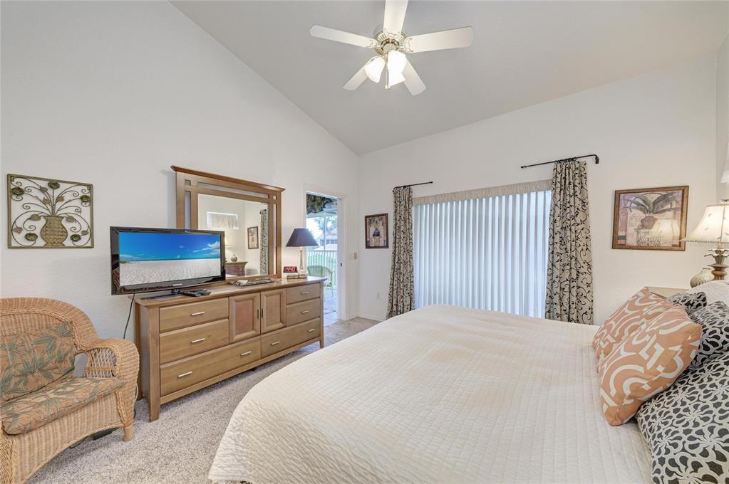 A bedroom features a king bed, a wooden dresser with a mirror, and a ceiling fan — 6821 FAIRVIEW TERRACE UNIT 6821, BRADENTON, FL
