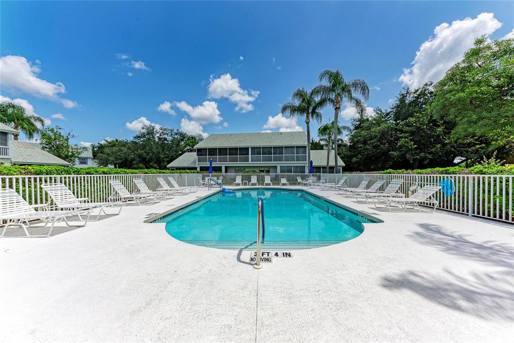 An outdoor swimming pool is surrounded by a white fence and lounge chairs — 6821 FAIRVIEW TERRACE UNIT 6821, BRADENTON, FL