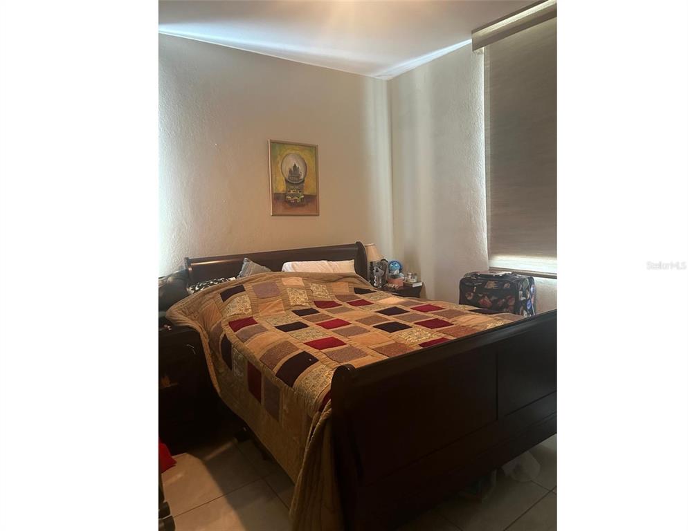 A bedroom features a dark wood bed frame, a patchwork quilt, and a framed wall picture — Mar Caspio M-6 PASEO LOS CORALES 2, DORADO, PR