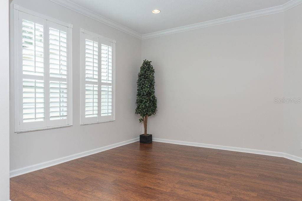 An empty room with light gray walls, dark wood flooring, and white plantation shutters — 107 CURRY RISE COURT, DELAND, FL
