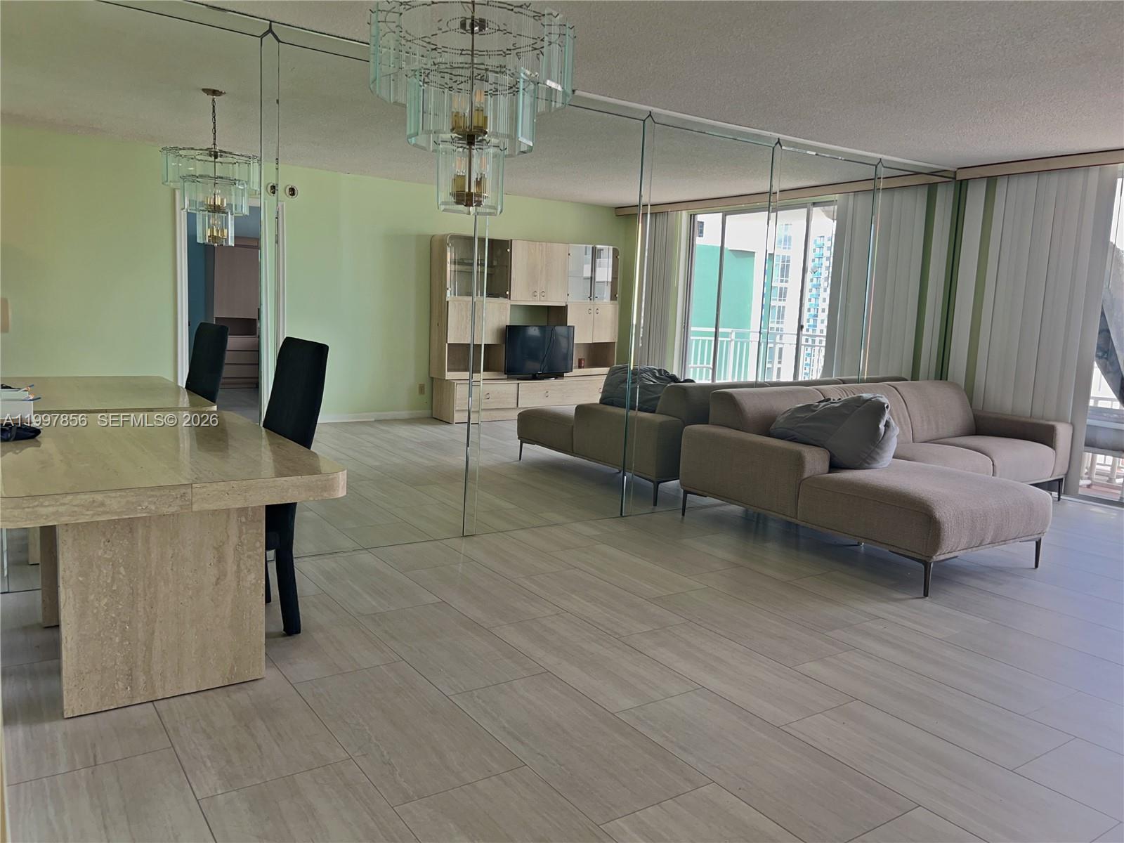 A living and dining area features light wood-look tile flooring and a mirrored accent wall — 1801 S Ocean Dr # 934, Hallandale Beach FL 33009, HALLANDALE BEACH, FL
