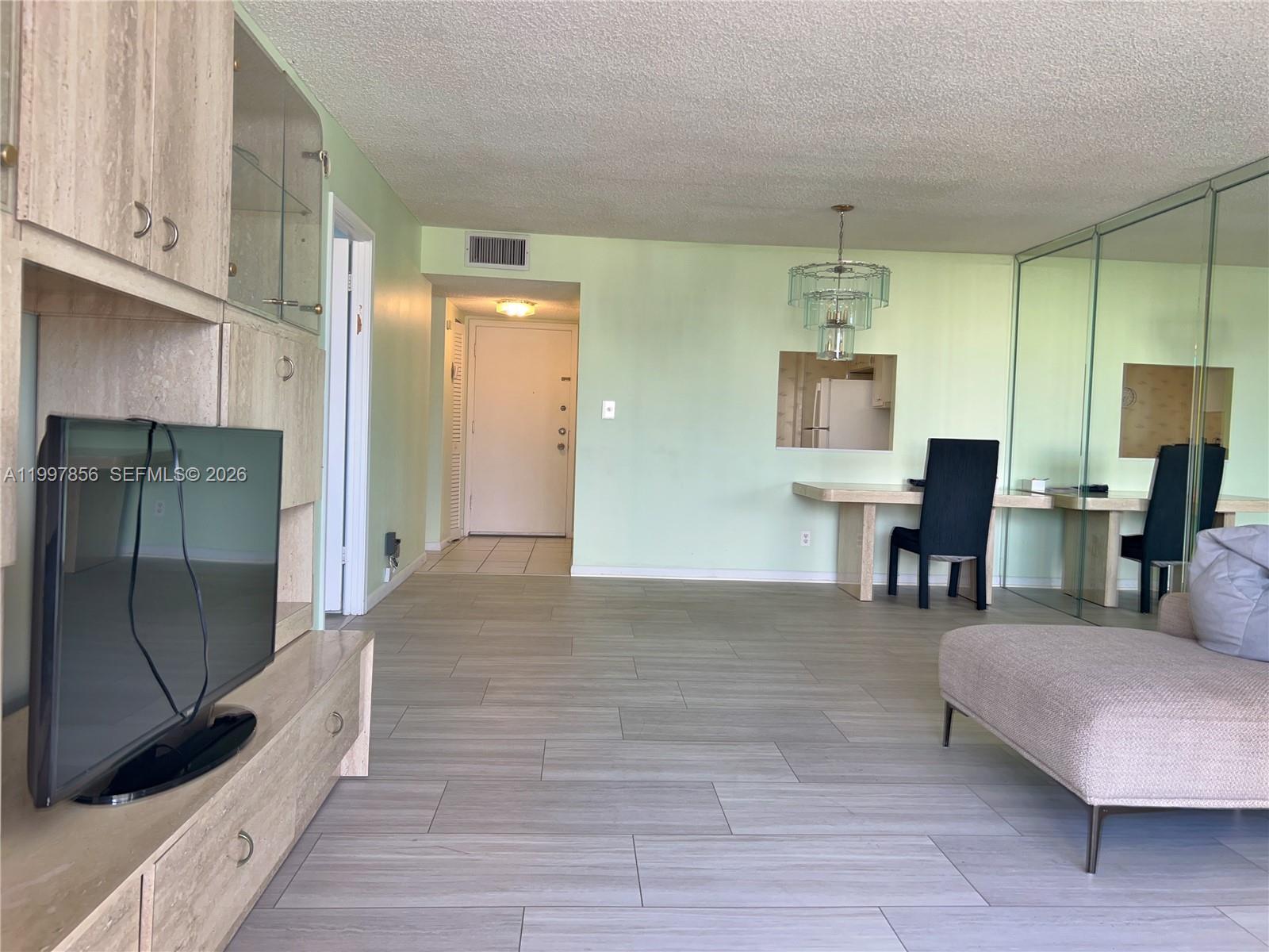 A living room features light green walls, wood-look tile flooring, and a built-in media unit — 1801 S Ocean Dr # 934, Hallandale Beach FL 33009, HALLANDALE BEACH, FL