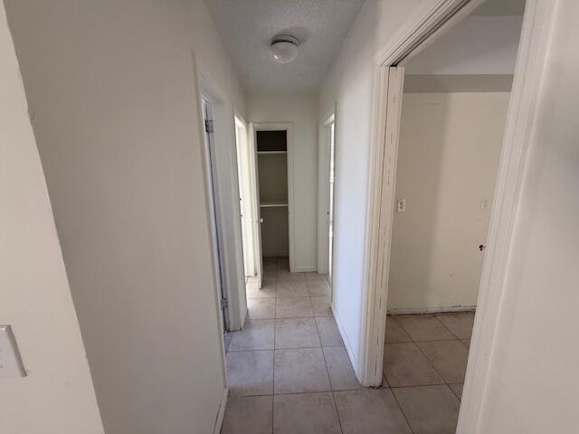 A hallway with light-colored tile flooring leads to a small closet at the end — 635 NW 5th Street, Boynton Beach FL 33435, BOYNTON BEACH, FL