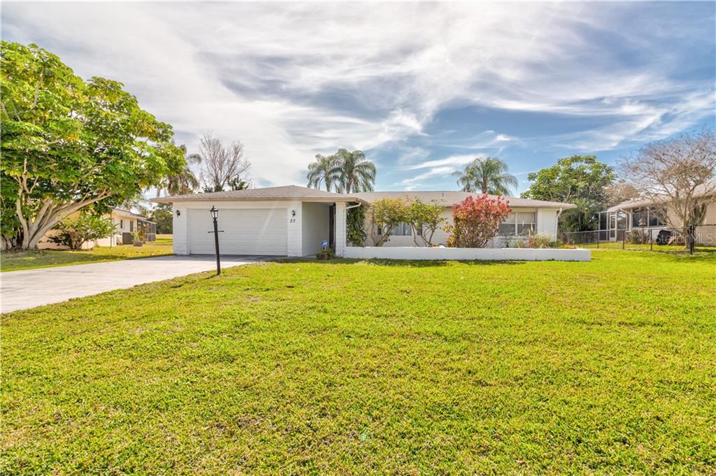 A single-story house with a white exterior, a two-car garage, and a large front lawn — 37 OAKLAND HILLS PLACE, ROTONDA WEST, FL