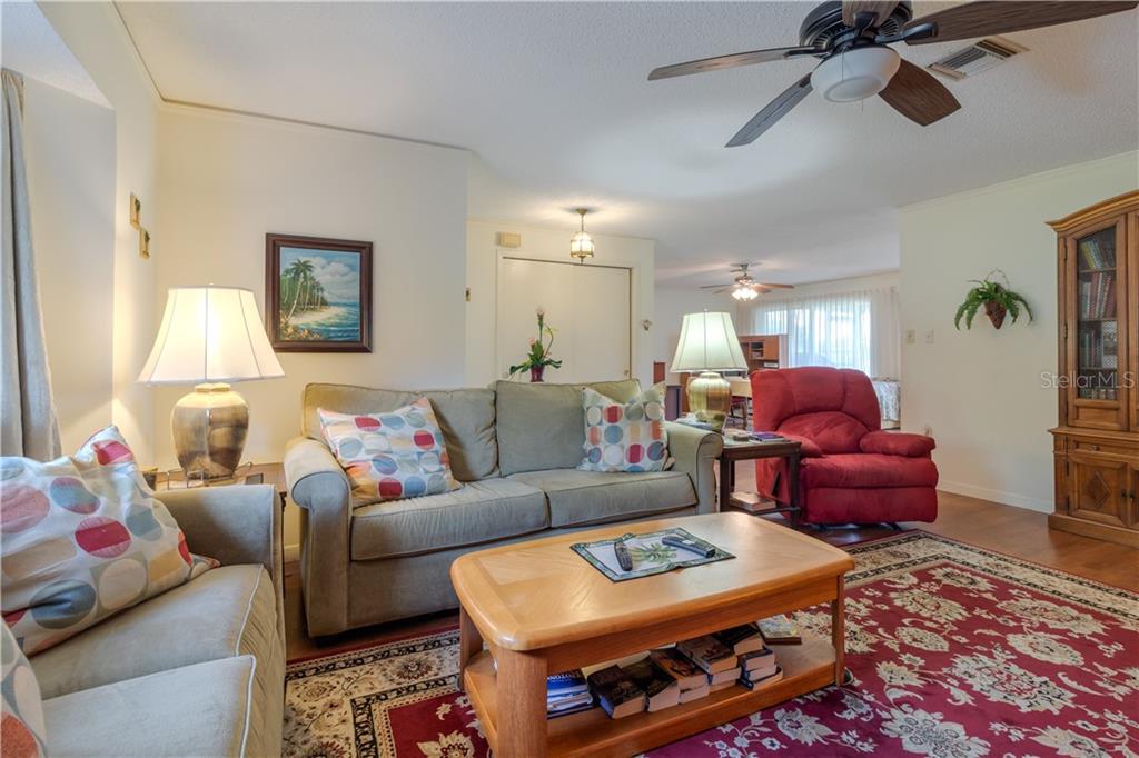 A living room features a sofa, a red recliner, a coffee table, and patterned area rugs — 37 OAKLAND HILLS PLACE, ROTONDA WEST, FL