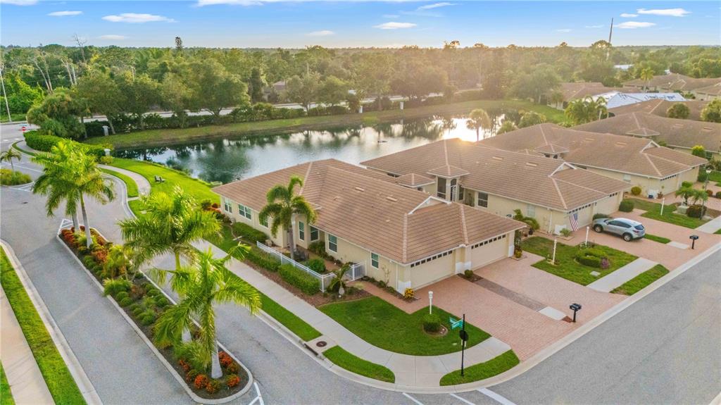 An aerial view of a suburban residential street with single-story homes bordering a small lake — 1001 TOPELIS DRIVE, ENGLEWOOD, FL