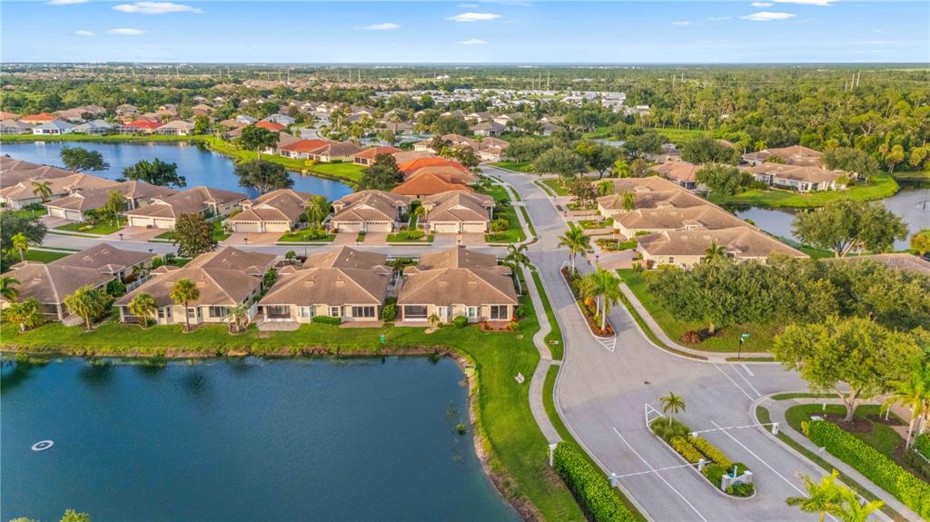 An aerial view shows a residential neighborhood with houses, a lake, and a gated entrance — 1001 TOPELIS DRIVE, ENGLEWOOD, FL