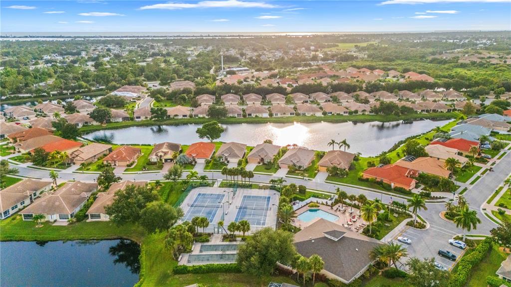 Aerial view of a residential neighborhood featuring a lake, tennis courts, and a community pool — 1001 TOPELIS DRIVE, ENGLEWOOD, FL