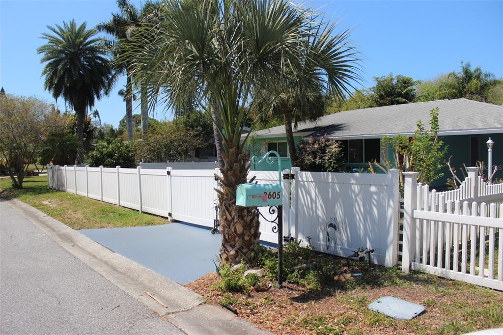 A turquoise house sits behind a white vinyl fence with a palm tree and mailbox — 3605 IROQUOIS AVENUE, SARASOTA, FL
