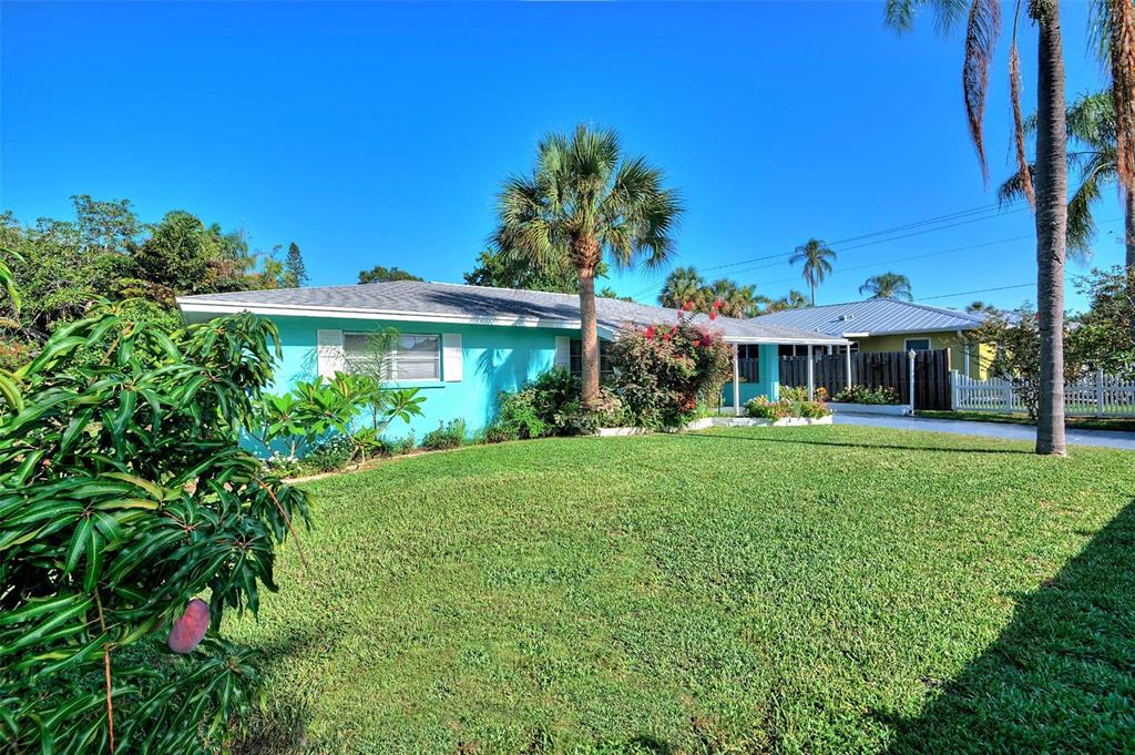 A turquoise single-story house with a palm tree in the front yard under a blue sky — 3605 IROQUOIS AVENUE, SARASOTA, FL