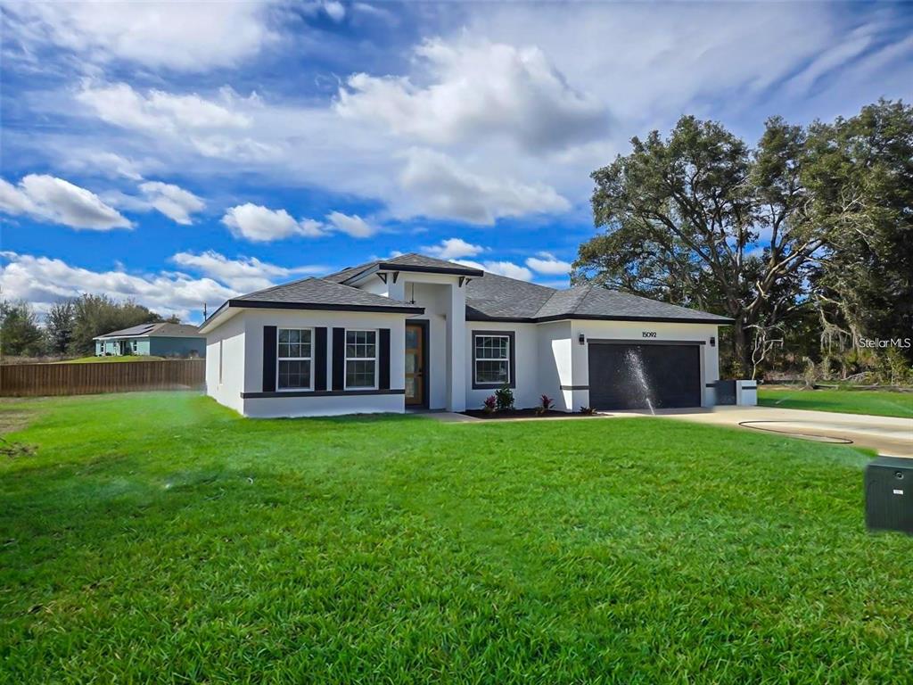 A single-story house with a white exterior, dark roof, and a two-car garage — 15092 SW 52ND COURT, OCALA, FL