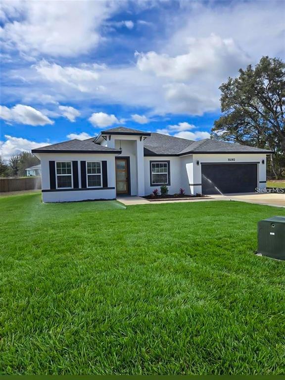 A single-story house with a white exterior, dark roof, and a two-car garage — 15092 SW 52ND COURT, OCALA, FL
