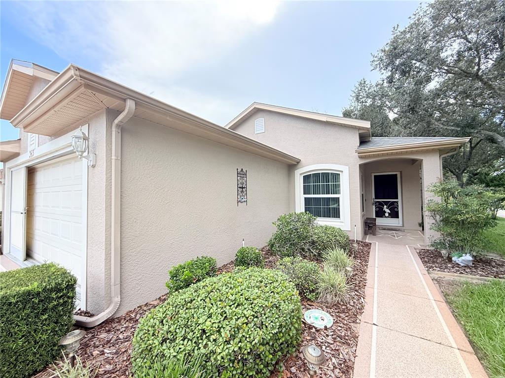A beige stucco house features a garage, a front walkway, and manicured landscaping — 265 CENTER OAK CIRCLE, SPRING HILL, FL