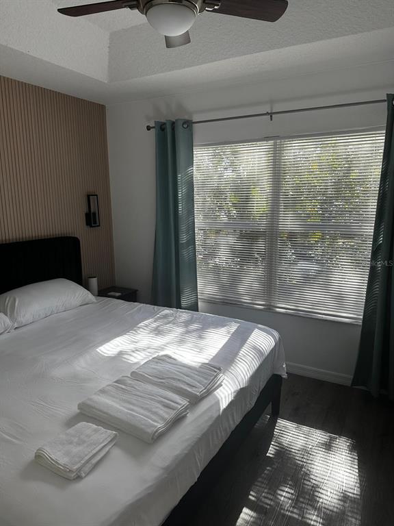 A bedroom features a bed with white linens, slatted wall paneling, and teal curtains — 5104 DOMINICA DRIVE, KISSIMMEE, FL