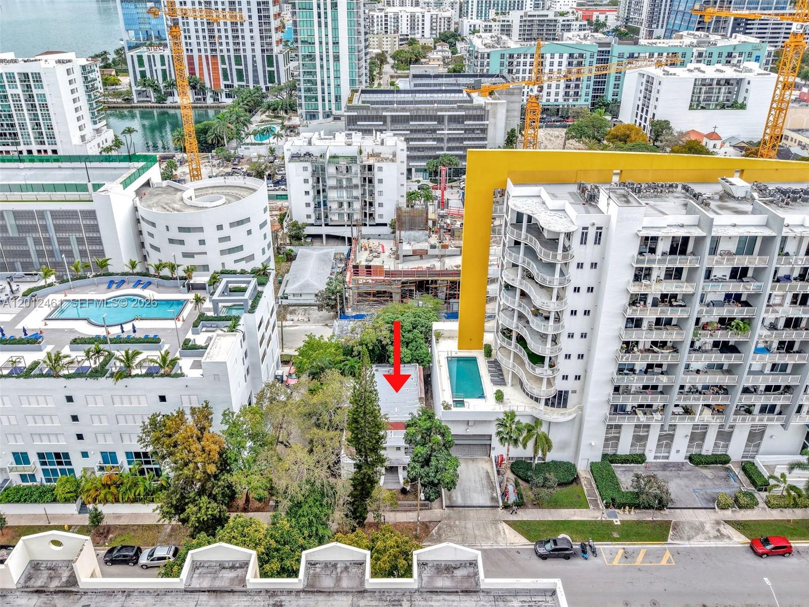 An aerial view shows a small house nestled between two large apartment buildings with pools — 452 NE 30th St, Miami FL 33137, MIAMI, FL