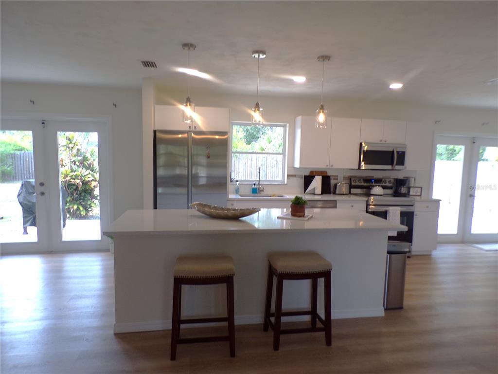 A modern kitchen features white cabinetry, stainless steel appliances, and a central island with seating — 1148 SALINA AVENUE, PORT CHARLOTTE, FL