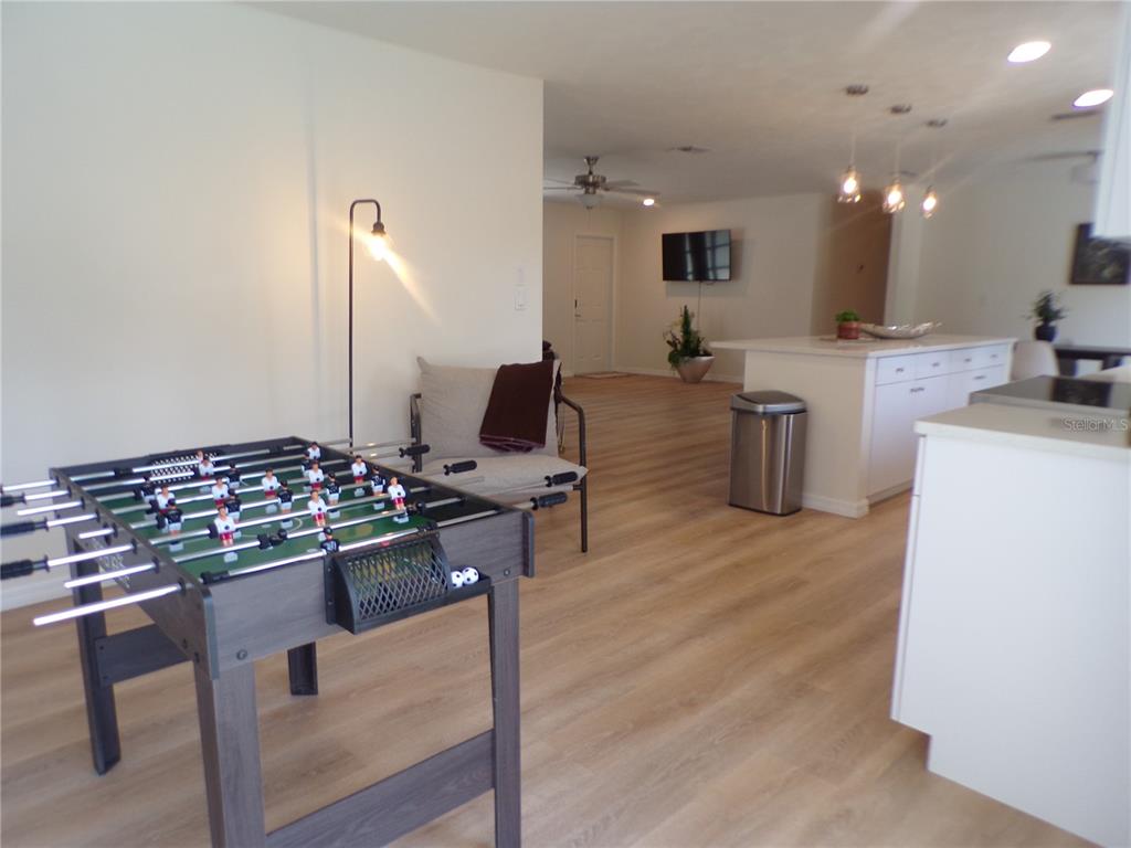 A foosball table sits in a room with light wood flooring and a kitchen island — 1148 SALINA AVENUE, PORT CHARLOTTE, FL
