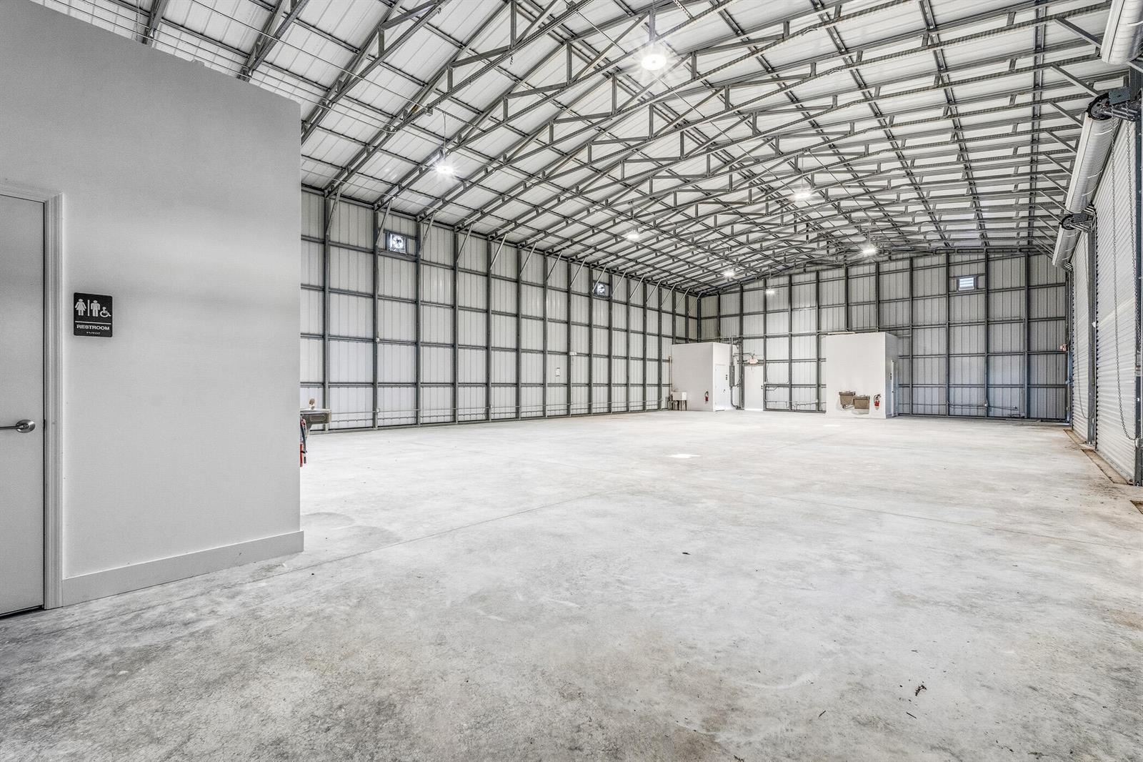 A large, empty industrial warehouse space features concrete floors, metal walls, and overhead lighting — VERO BEACH, FL