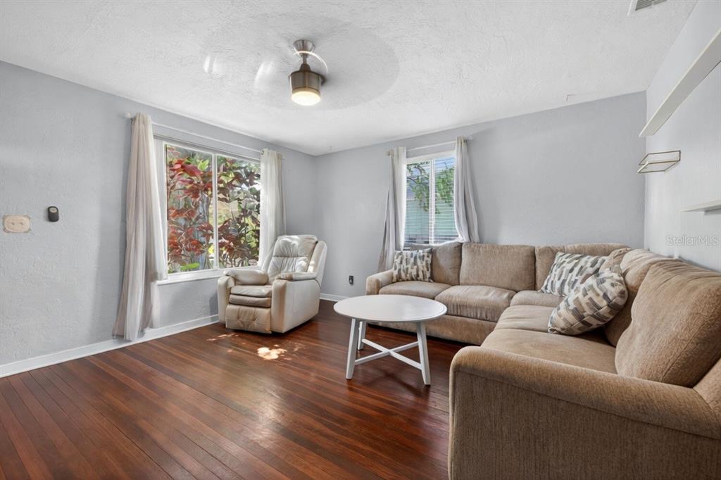 A living room features a beige sectional sofa, a recliner, and dark hardwood flooring — 1213 55TH STREET S, GULFPORT, FL