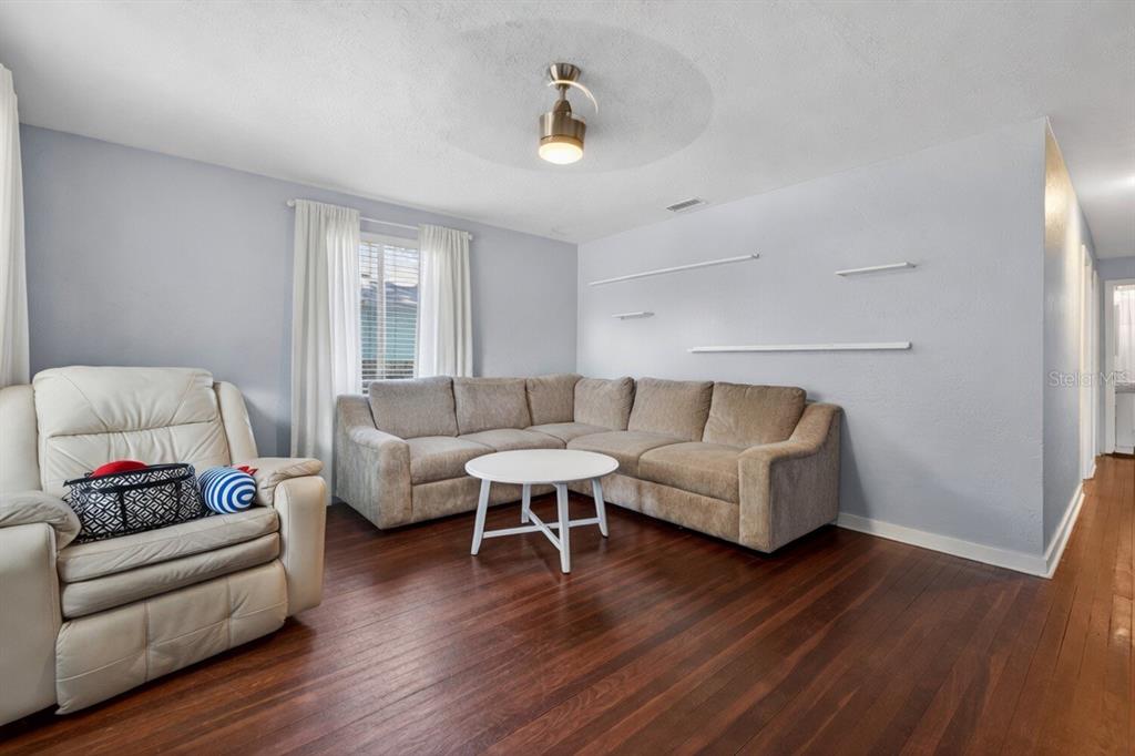 A living room features a sectional sofa, a white coffee table, and wood flooring — 1213 55TH STREET S, GULFPORT, FL