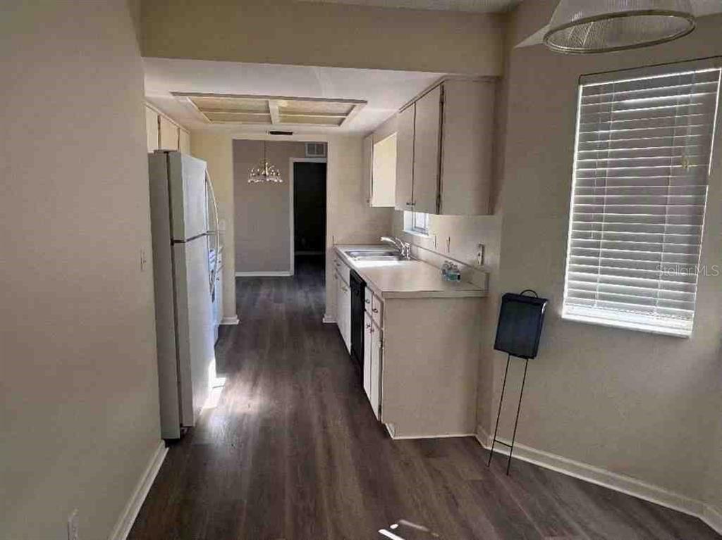 A kitchen features white cabinets, a refrigerator, a sink, and wood-look flooring — 5110 NW 19TH PLACE, OCALA, FL