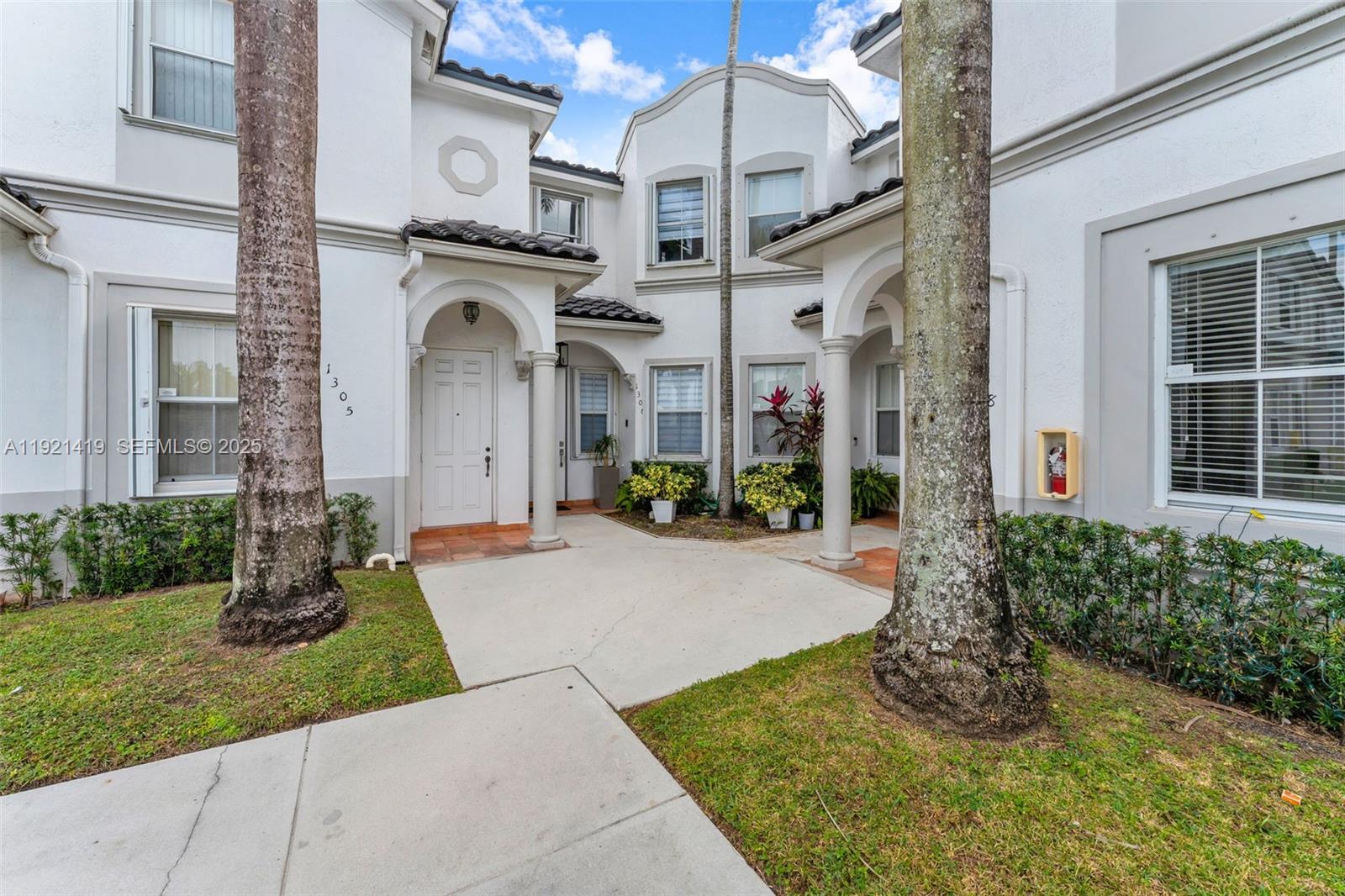 A view of the exterior entrance to two white townhomes with palm trees — 5610 NW 107th Ave # 1306, Doral FL 33178, DORAL, FL