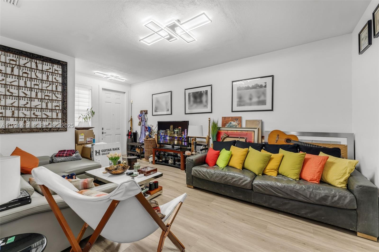 A living room features a grey sofa with colorful pillows, a white chair, and light flooring — 5610 NW 107th Ave # 1306, Doral FL 33178, DORAL, FL