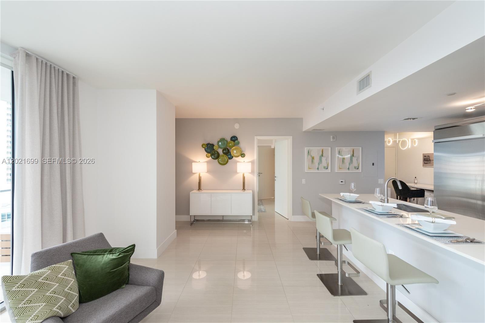 A modern living area features a kitchen island with bar stools and a console table — 1300 Brickell Bay Dr # 2900, Miami FL 33131, MIAMI, FL