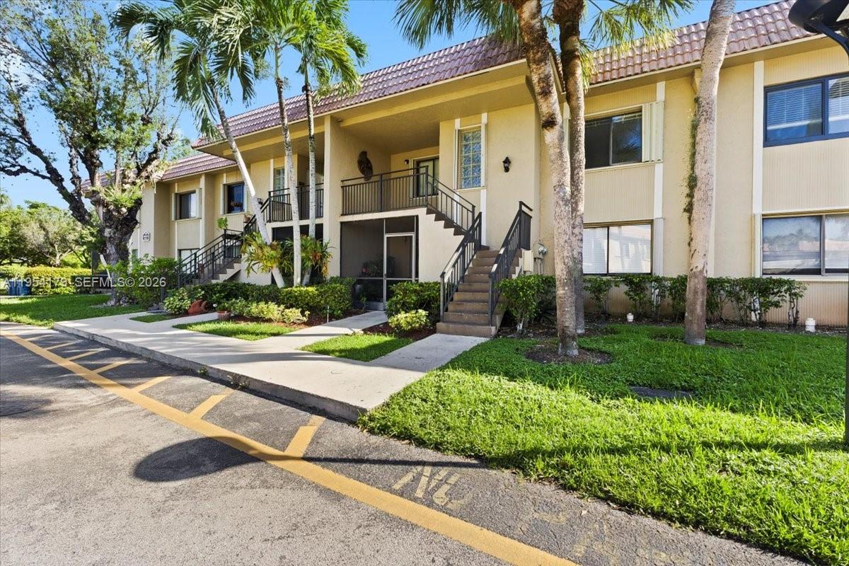 A two-story apartment building features beige stucco walls, a tiled roof, and exterior staircases — 302 Lakeview Dr # 203, Weston FL 33326, WESTON, FL