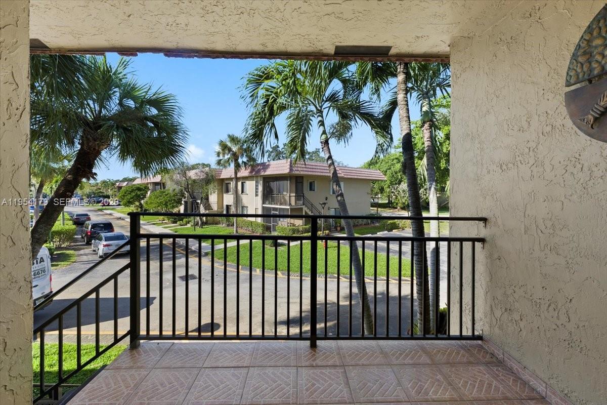 A tiled balcony with a black metal railing overlooks a parking lot and palm trees — 302 Lakeview Dr # 203, Weston FL 33326, WESTON, FL
