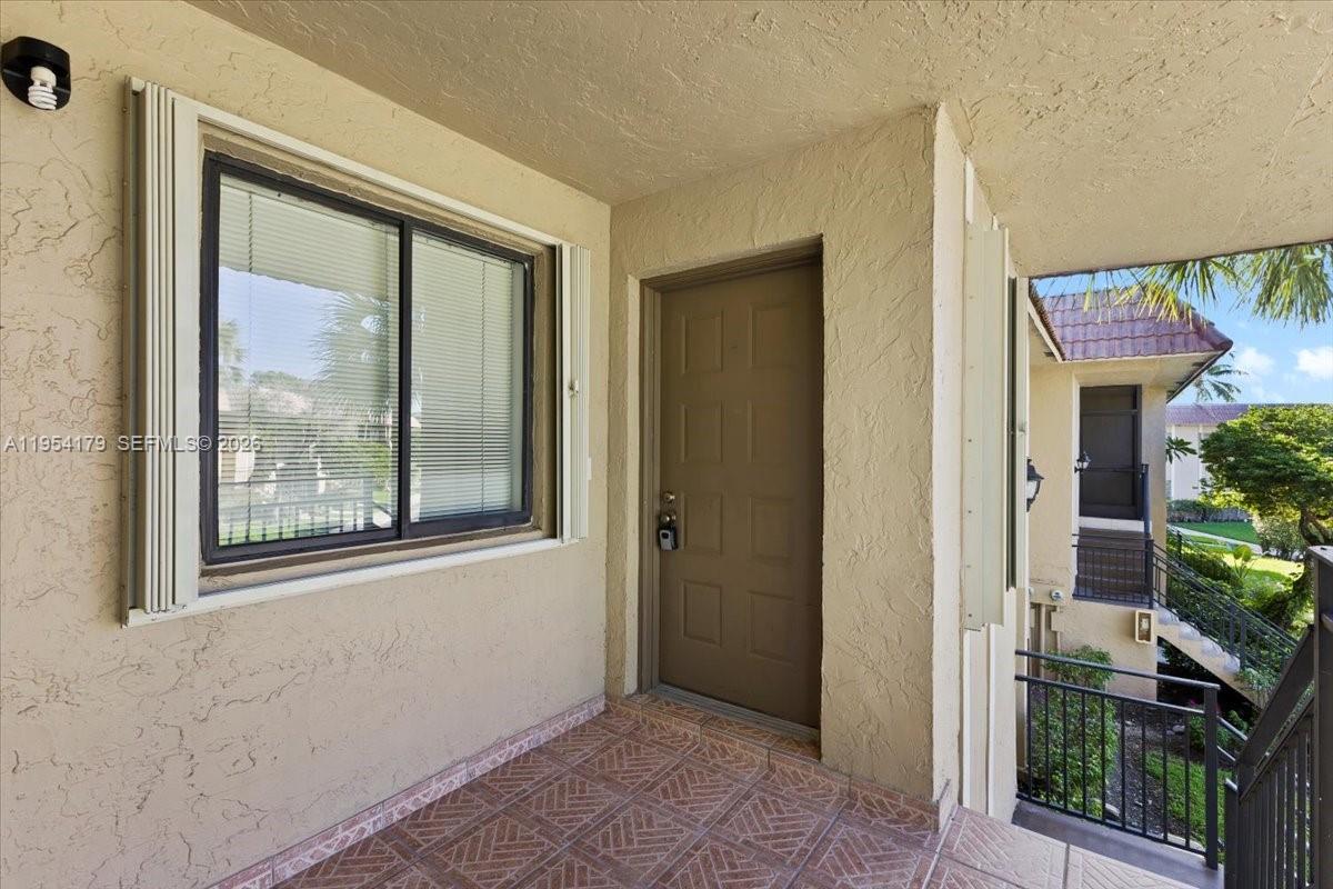 A covered entryway features a tiled floor, a window with blinds, and a brown door — 302 Lakeview Dr # 203, Weston FL 33326, WESTON, FL