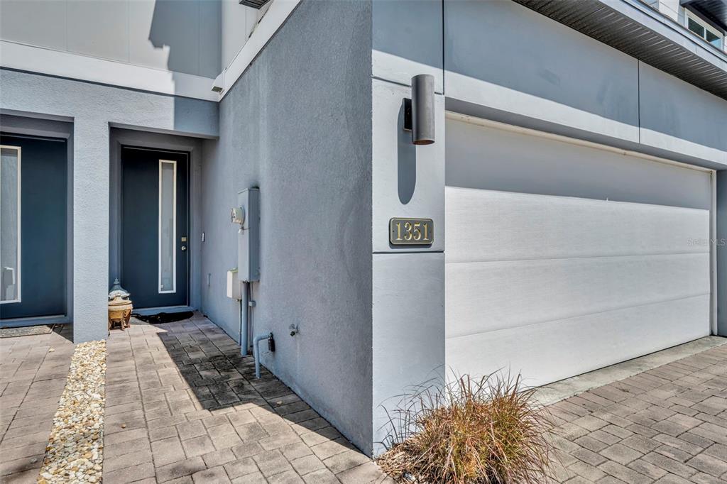 The exterior of a modern home features a gray wall, a garage door, and a doorway — 1351 MERRYDALE WAY, WINTER PARK, FL