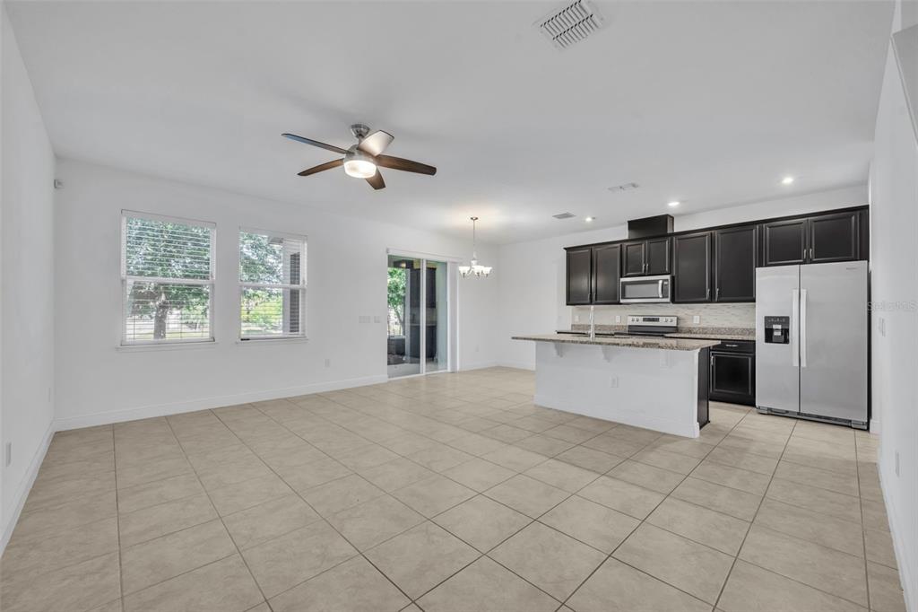 An open-concept kitchen and living area featuring dark cabinetry, tile flooring, and a ceiling fan — 1351 MERRYDALE WAY, WINTER PARK, FL