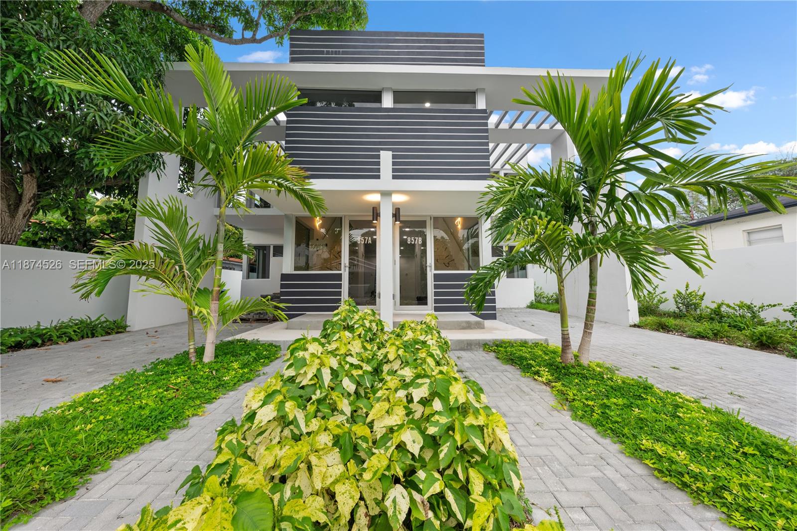 A modern two-story duplex with dark horizontal siding, glass entry doors, and palm trees — 857 SW 14th Ave # A, Miami FL 33135, MIAMI, FL