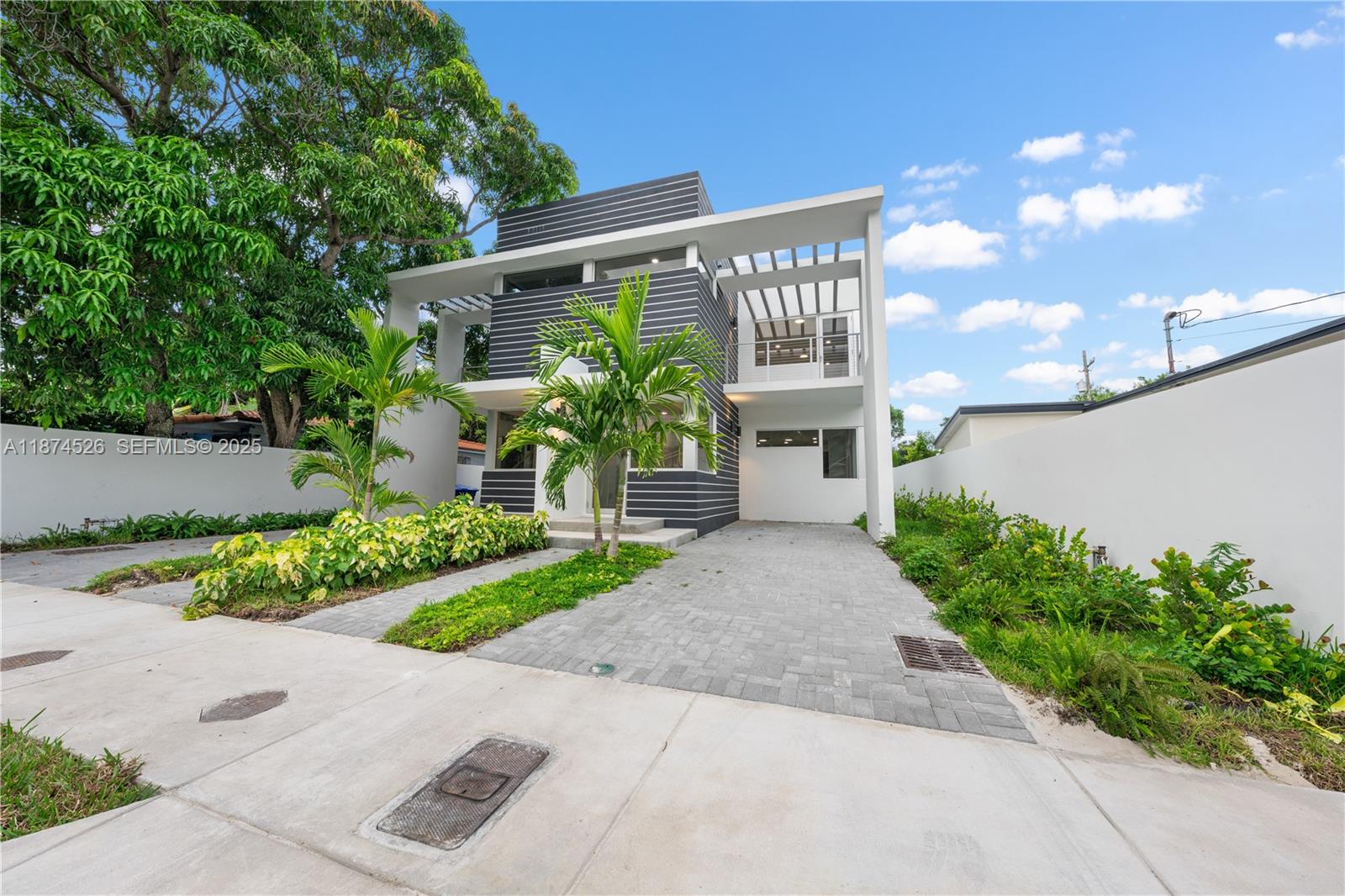 A modern two-story house features a dark horizontal-slatted facade, a white frame, and a paved driveway — 857 SW 14th Ave # A, Miami FL 33135, MIAMI, FL
