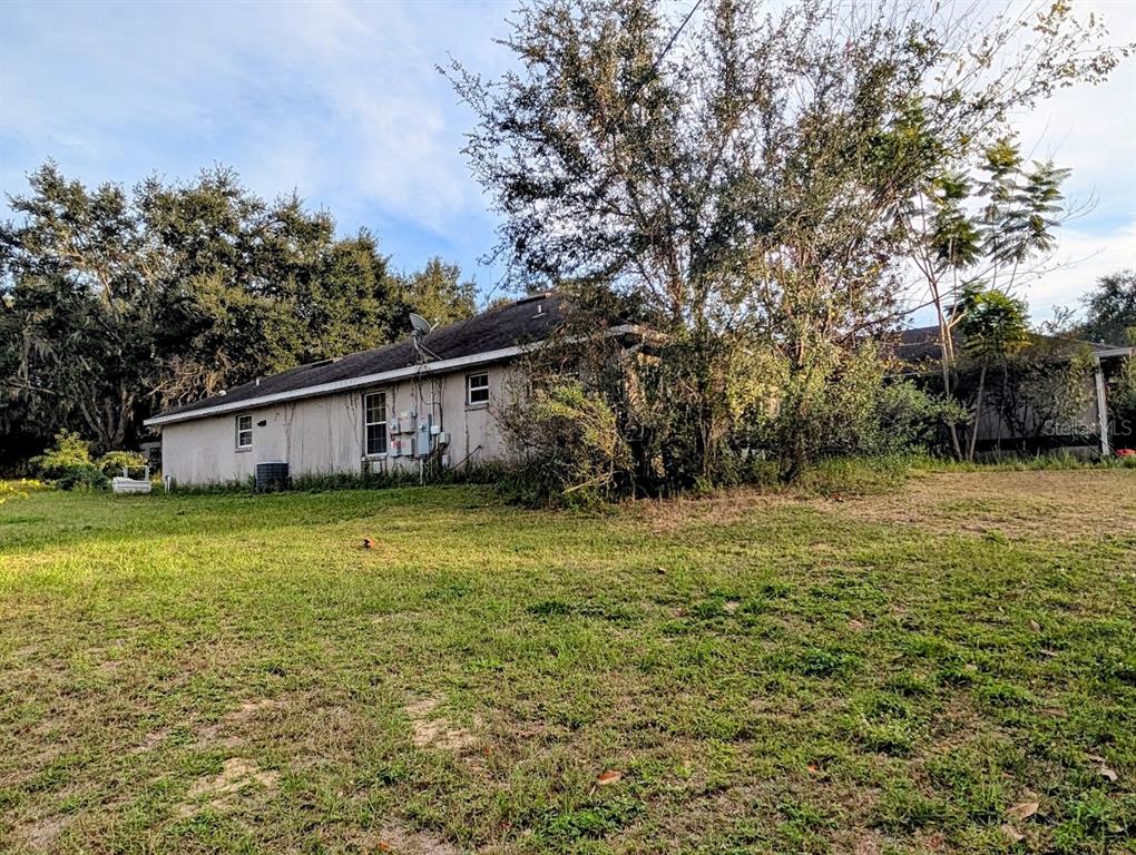 The exterior of a single-story house with a light-colored facade and a dark shingled roof — 310 TOMATO HILL ROAD, LEESBURG, FL