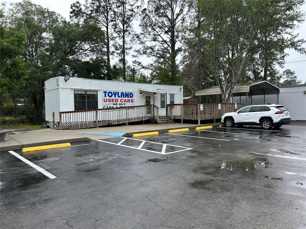 A white modular building with a wooden ramp and deck serves as a used car dealership — 241 NE 39TH AVENUE, GAINESVILLE, FL